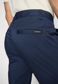 Mornarsko modri hlače iz gladkega blaga s ravnim krojem. Imajo zadnji žep in oznako logotipa Calvin Klein nad žepom.