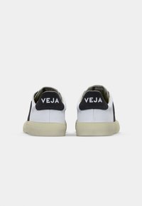 Biele a čierne sneakers s textúrovaným plátnom, s kontrastnou čiernou pätou a jemným logom na zadnej strane. Gumová podrážka.