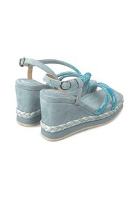 Sandali wedge azzurri con finitura in suede testurizzato, cinturini blu scintillanti e un accento di corda intrecciata attorno alla base.