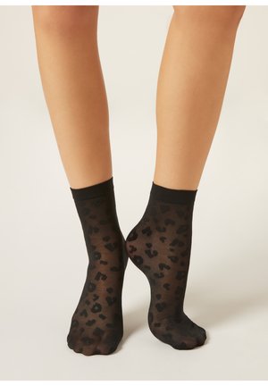 Transparente schwarze Socken mit einem Leopardenmuster in dunklen Farbtönen. Sie haben eine feste, schwarze Manschette oben und eine glatte Textur.