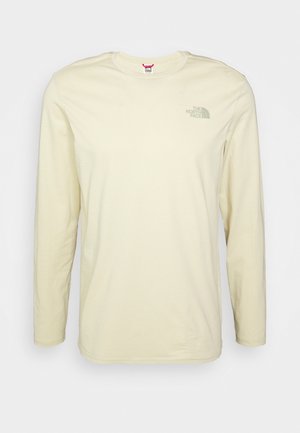 Koszulka z długim rękawem w kolorze ecru z okrągłym dekoltem i logo The North Face na lewej piersi, pokazana na jednolitym jasnym tle.