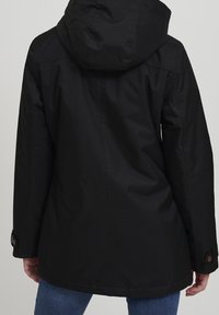 Schwarze wasserdichte Jacke mit Kapuze, langen Ärmeln mit geknöpften Manschetten und geradem Schnitt. Glatte Textur mit minimalen Nähten.