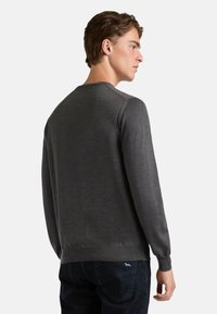 Maglione grigio scuro realizzato in tessuto morbido, con scollo rotondo, maniche lunghe e polsini a costine, dalla texture liscia e design minimalista.