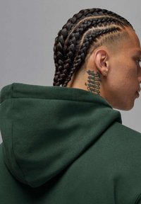 Ciemnozielona bluza z kapturem o fakturowanej tkaninie, z kapturem oraz zbliżenie na zaplecione włosy i tatuaż na szyi.