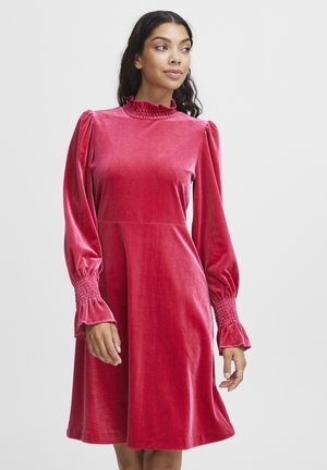 Samtiges rosa Kleid mit hohem Rüschkragen, aufgeblähten Ärmeln und gesmokten Bündchen, das eine lockere A-Linien-Silhouette und einen knielangen Saum aufweist.