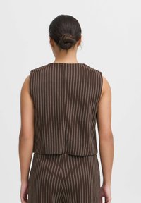 Top marron sans manches avec des rayures verticales blanches, présentant un col arrondi et une texture de tissu lisse, montré de dos.