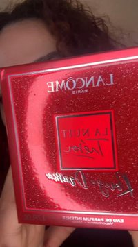 Person hält glänzende rote Lancôme Paris La Nuit Trésor Parfüm-Geschenkbox mit silbernem und schwarzem Text in Nahaufnahme.