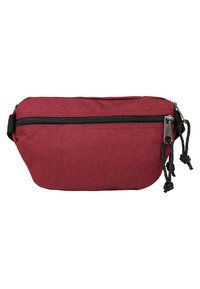 Bolso de cintura rojo de tela con cierre de cremallera superior, ribete negro en la cremallera y correas ajustables negras. Textura suave con un diseño simple.