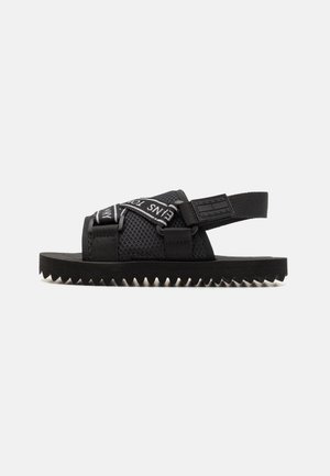 Zwarte sandalen met een bovenwerk van mesh, verstelbare banden met witte branding en een gegroefde rubberen zool voor grip.