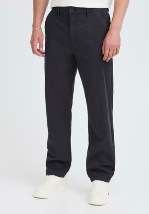 Black cotton trousers with a straight fit, featuring a button closure and front pockets, paired with white sneakers. Simple, classic design.