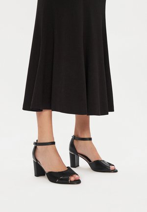 Décolleté neri con punta aperta, con una parte anteriore texturizzata e cinturino alla caviglia. Design con tacco a blocco e finitura liscia che valorizzano l'aspetto complessivo.