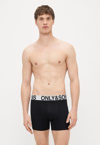 Czarne bokserki z bawełny z białym pasem w talii, na którym czarnym drukiem widnieje napis „ONLY & SONS”. Materiał jest gładki i dopasowany.
