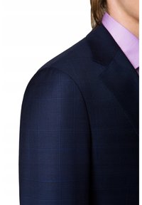 Granatowa marynarka w kratę z wyraźnymi ramionami i klapami o charakterystycznym kształcie, zestawiona z jasnofioletowym, kratkowanym kołnierzykiem koszuli. Gładka tekstura materiału.