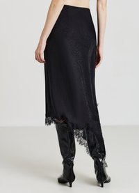Jupe noire en tissu texturé, ornée d'un ourlet en dentelle. Le design est droit avec une fente sur le côté et a une finition lisse.