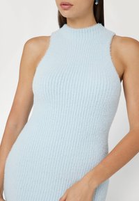 Top senza maniche in maglia a costine blu chiaro, con colletto alto e texture morbida, caratterizzato da una silhouette aderente e dettagli minimi.