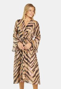 Lang, vloeiende jurk van doorzichtig materiaal met een golvend chevronpatroon in tinten bruin, roze en zwart; aangedekte taille, V-hals en klokmouwen.