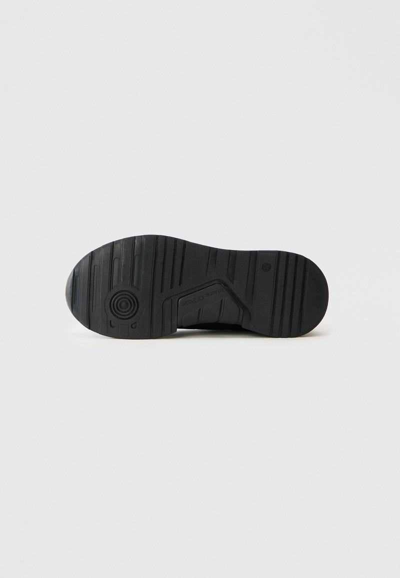 Schwarze Sneaker-Sohle mit strukturiertem Grip-Muster und runder Logodetail. Hergestellt aus Gummi, mit verschiedenen Tiefenrillen für besseren Halt.