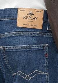 Τα μπλε τζιν από denim διαθέτουν δερμάτινο ταμπελάκι με την επωνυμία "REPLAY", ραφές λεπτομέρειες στις τσέπες και κλασικό σχέδιο με πέντε τσέπες.