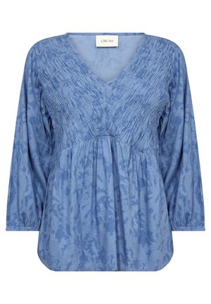 Blouse bleue à col en V avec texture froncée, manches longues et ourlet droit. Motif floral subtilement visible sur le tissu. Marque : Cream.