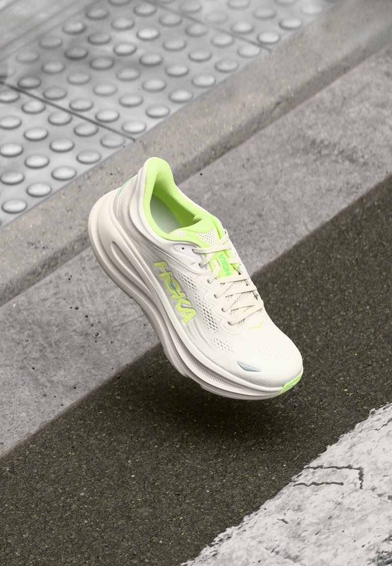 Λευκό αθλητικό παπούτσι με υφή από δίχτυ στο πάνω μέρος, λεπτομέρειες σε νέον πράσινο, μαλακή σόλα και λογότυπο της μάρκας στο πλάι. Ελαφρύ σχεδιασμό.