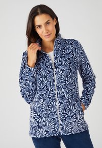Giacca di pile con sfondo blu navy, caratterizzata da un motivo floreale bianco. Ha un colletto alto, zip frontale e tasche laterali.