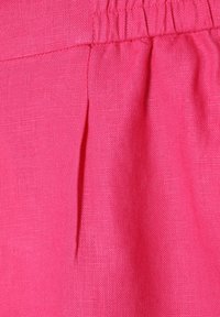 Bright pink fabric with a textured weave, featuring a pleated detail near the waistband. The material appears lightweight and breathable.