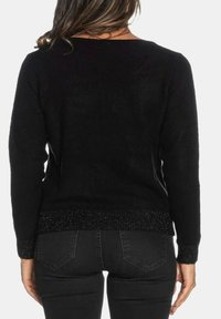 Maglione nero con maniche lunghe e scollo ampio. Presenta un orlo testurizzato e scintillante di colore nero. Abbinato a jeans scuri, con dettagli visibili sul retro.
