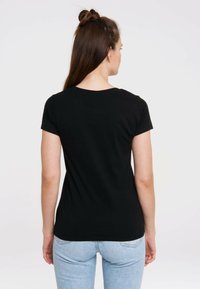 Black short-sleeve t-shirt made of cotton, featuring a round neckline and a fitted silhouette, worn with light blue jeans.