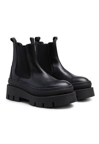 Bottes Chelsea en cuir noir avec panneaux latéraux en élasthanne, semelles de plateforme robustes et détails en caoutchouc texturé. Fini lisse et forme de bout arrondi.