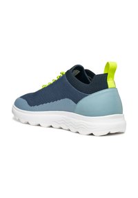 Sneaker blu navy e azzurro chiaro con tomaia in maglia testurizzata, suola bianca a motivo ondulato e lacci e linguetta del tallone verde neon.