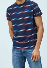 Camiseta de rayas azul y roja con cuello redondo, mangas cortas y un pequeño logo en el pecho; fabricada con una suave mezcla de algodón.