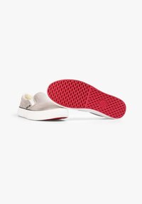 Graue Leinenschlupfschuhe mit einer weißen Sohle und einer roten strukturierten Gummisohle. Sie verfügen über ein weiches Innenfutter und seitliche elastische Einsätze für einen einfachen Einstieg.