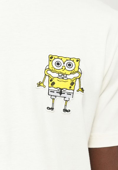 Vit bomull t-shirt med en broderad, färgglad design av SpongeBob Fyrkant på vänster bröstområde. Enkel rund halsdesign.