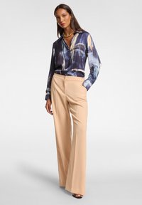 Blusa a righe navy e crema con colletto, abbinata a pantaloni a gamba larga crema con chiusura a bottone. Tessuto testurizzato, drappeggio elegante.