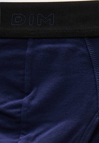Gros plan sur un caleçon pour homme bleu marine avec une ceinture noire ornée du logo DIM en relief au centre avant.