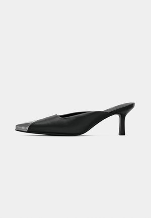Black pointed-toe mule with a low kitten heel and a silver metallic tip, displayed on a plain white background.