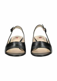 Les sandales à talon noir en cuir avec un design à bout ouvert, une sangle croisée et une boucle ajustable. L'intérieur est beige avec le logo de la marque.