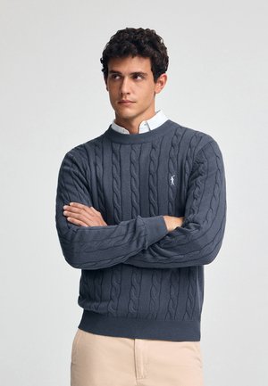 Grauer Kabelstrickpullover aus weichem Stoff, mit rundem Halsausschnitt, gerippten Manschetten und einem kleinen Logo auf der linken Brust.