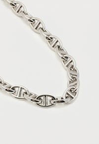 Ασημένιο κολιέ με αλυσίδα και γυαλιστερές οβάλ συνδέσεις που διαθέτουν κάθετη οπή σε κάθε σύνδεσμο, τοποθετημένο σε λευκό φόντο.