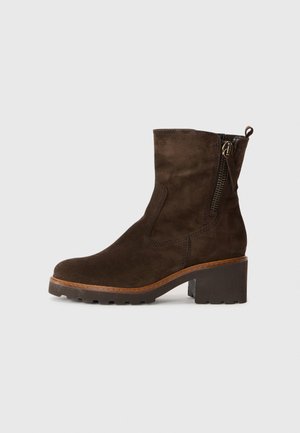 Stivale ankle in suede marrone con tacco spesso, zip laterale e suola testurizzata; finitura liscia con dettagli di cucitura visibili.