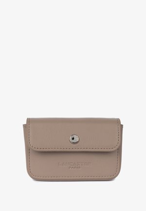 Porte-cartes en cuir beige avec un rabat, un bouton pression argenté et le logo "LANCASTER PARIS" embossé sur le devant. Présente des coutures soignées.
