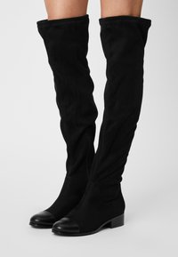 Black over-the-knee boots in soft suede with a rounded toe, featuring a matte black cap toe and side zipper, low block heel design.