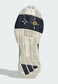 Suola di scarpa con una texture in gomma a motivo, caratterizzata da una sezione nera al centro e un dettaglio circolare giallo, con bordi più chiari.