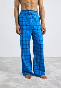 Blauwe geruite pyjamabroek met een losse pasvorm, elastische tailleband en trekkoordsluiting. Gemaakt van zachte stof, met een ruitpatroon.