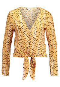 Gul långärmad skjorta med knappar och brun leopardmönster, djup V-ringning och en knut framtill vid midjan.