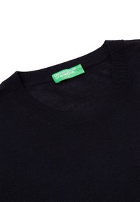 Tmavě navy modrý pletený svetr s výstřihem, uvnitř límce je přišitá zelená etiketa "United Colors of Benetton".