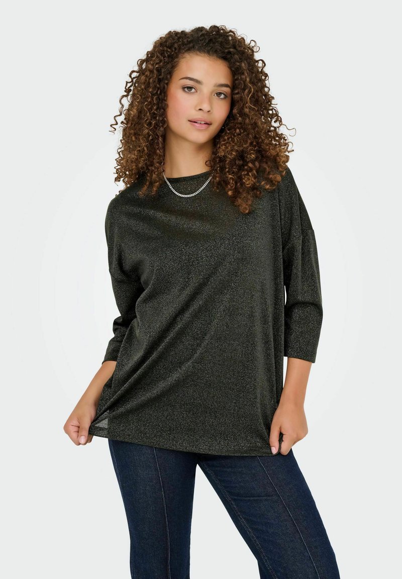 Camiseta negra con un corte relajado, mangas de tres cuartos y un acabado brillante y texturizado. Combinada con jeans de mezclilla oscuros.