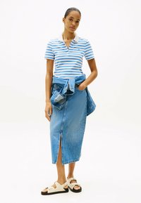 Blå og hvid stribet polo skjorte, denim midi nederdel med split, lagdelt denimjakke med knudedetalje i taljen og beige sandaler med sorte såler.