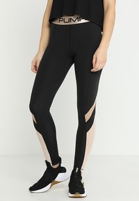 Leggings neri con dettagli a taglio e un pannello rosa pallido. Presentano un cinturino alto con il marchio "PUMA". Realizzati in un materiale liscio e elastico.
