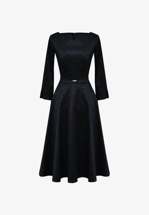 Czarna sukienka z teksturowanym wzorem, dopasowanym górnym częścią i rozkloszowanym dołem. Posiada długie rękawy, okrągły dekolt oraz złoty akcent w talii.